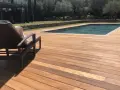 Terrasse en bois ipe vieilli, invitant à la détente au bord de la piscine sous le soleil.