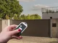 Main tenant utilise une télécommande pour le réglage du gond d'un portail aluminium.