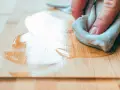 Main d'une personne appliquant de l'huile sur un plan de travail en chêne massif pour le protéger.