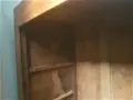 Intérieur d'une armoire ancienne en bois, prête à démonter. Les étagères sont visibles, ainsi que les marques du temps.