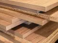 Pile de panneaux de bois, certains avec un placage imitant le bois, d'autres montrant leur cœur granuleux. Les inconvénients du bois MDF incluent sa sensibilité à l'humidité.