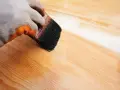 Application d'un vernis protecteur pour le traitement plan de travail bois. La brosse dépose une couche uniforme sur le bois clair.