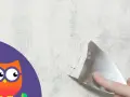 Maintenant, il faut enlever la peinture d'un mur avec une spatule. Un hibou curieux observe.