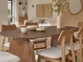 Table et chaises en bois mindi dans une salle à manger lumineuse. Des bols décoratifs et une plante apportent une touche naturelle.