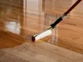 Application d'un vernis ou vitrificateur sur un parquet en bois. Le rouleau dépose une couche brillante et protectrice.