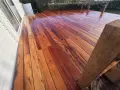 Planches de muiracatiara grisé, un bois exotique aux teintes chaudes et veinures marquées, formant une terrasse éclatante.