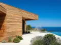 Maison moderne aux parements en bois de douglas ou pin, avec piscine à débordement et vue sur la mer.