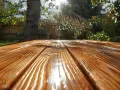 Table en bois fraîchement traitée avec un gel protection bois ou lasure, reflétant le soleil dans un jardin verdoyant.