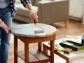 Application d'une sous-couche grise sur une table en bois. Le résultat avant/après du decapant bois est visible.