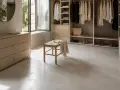 Un dressing lumineux avec un meuble en béton ciré, des vêtements suspendus et un banc en bois.