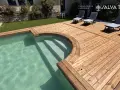 Terrasse en bois autour d'une piscine avec des chaises longues.