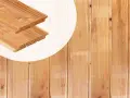 Planches de bois de mélèze ou douglas, avec leurs rainures et languettes, prêtes à être assemblées pour un projet de construction.