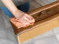 Maintenant, je sais comment nettoyer un meuble avant de le peindre. Une main passe un chiffon orange sur un tiroir en bois verni.