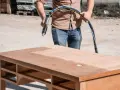 Un homme utilise un appareil pour le décapage chimique bois d'un bureau. La moitié de la surface est déjà propre.