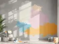 Peinture sur mur ciment intérieur avec des éclaboussures de couleurs vives. Des pots de peinture et des pinceaux sont disposés au sol, prêts pour un projet créatif.