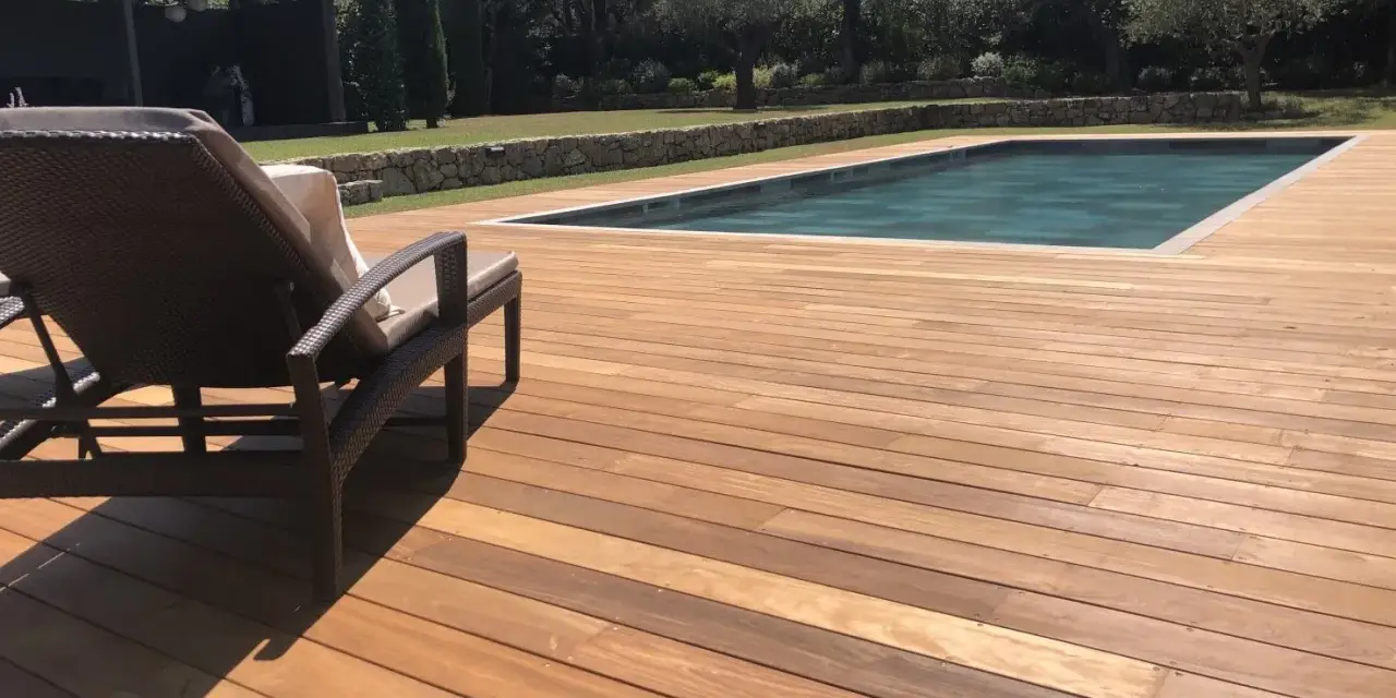 Terrasse en bois ipe vieilli, invitant à la détente au bord de la piscine sous le soleil.