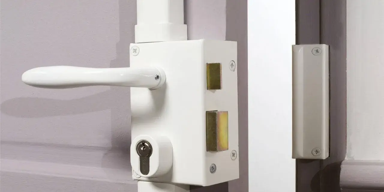 Détail du fonctionnement du barillet de serrure sur une porte blanche. Le mécanisme est visible avec sa poignée et son cylindre.