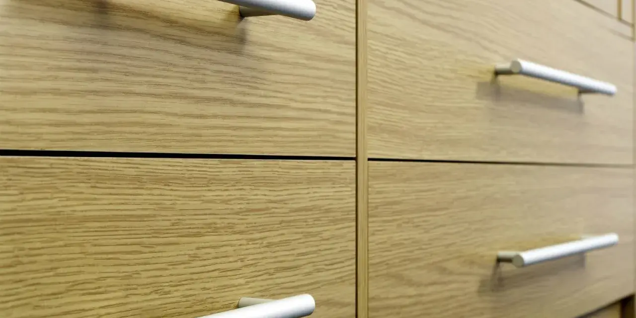 Poignées de tiroirs en aluminium sur des meubles en bois clair. Un guide visuel pour comment fixer un bouton de meuble.