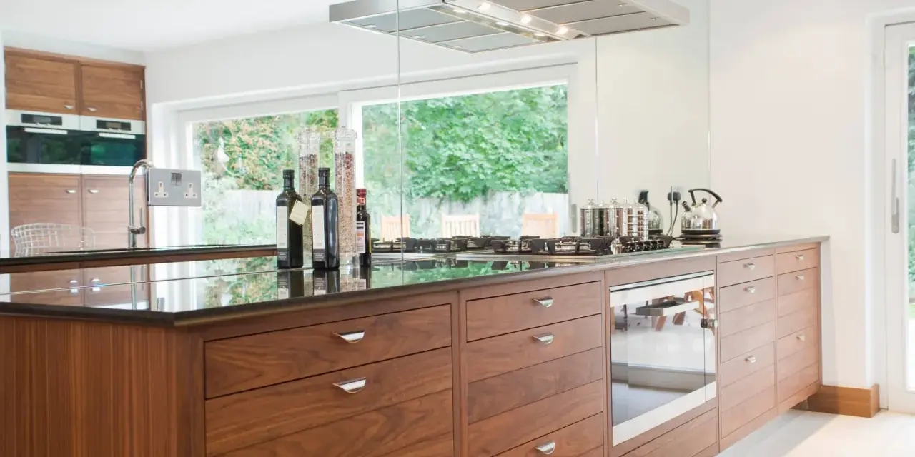 Cuisine moderne avec îlot central en bois, plan de travail en granit noir, et électroménagers intégrés. Une rénovation cuisine bois réussie.