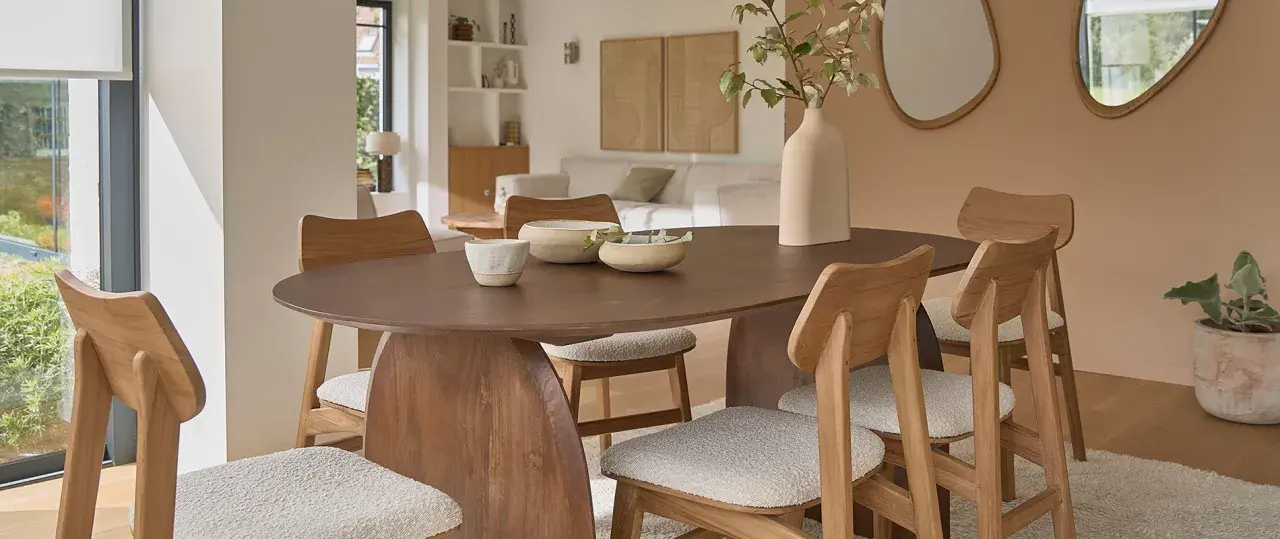 Table et chaises en bois mindi dans une salle à manger lumineuse. Des bols décoratifs et une plante apportent une touche naturelle.