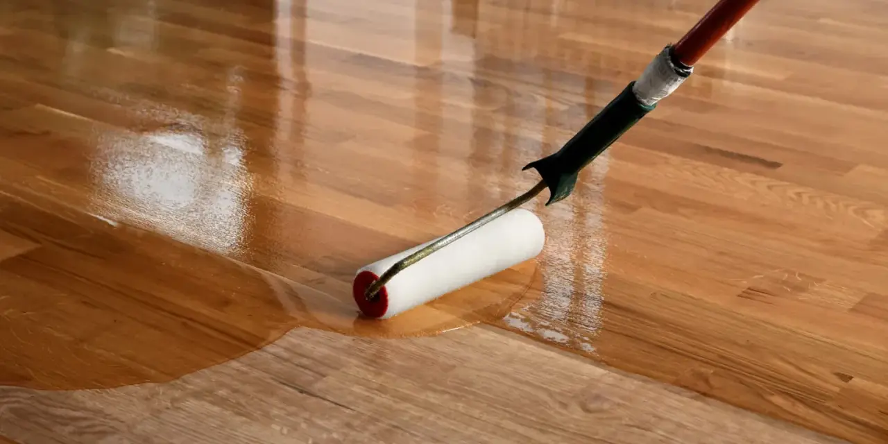 Application d'un vernis ou vitrificateur sur un parquet en bois. Le rouleau dépose une couche brillante et protectrice.