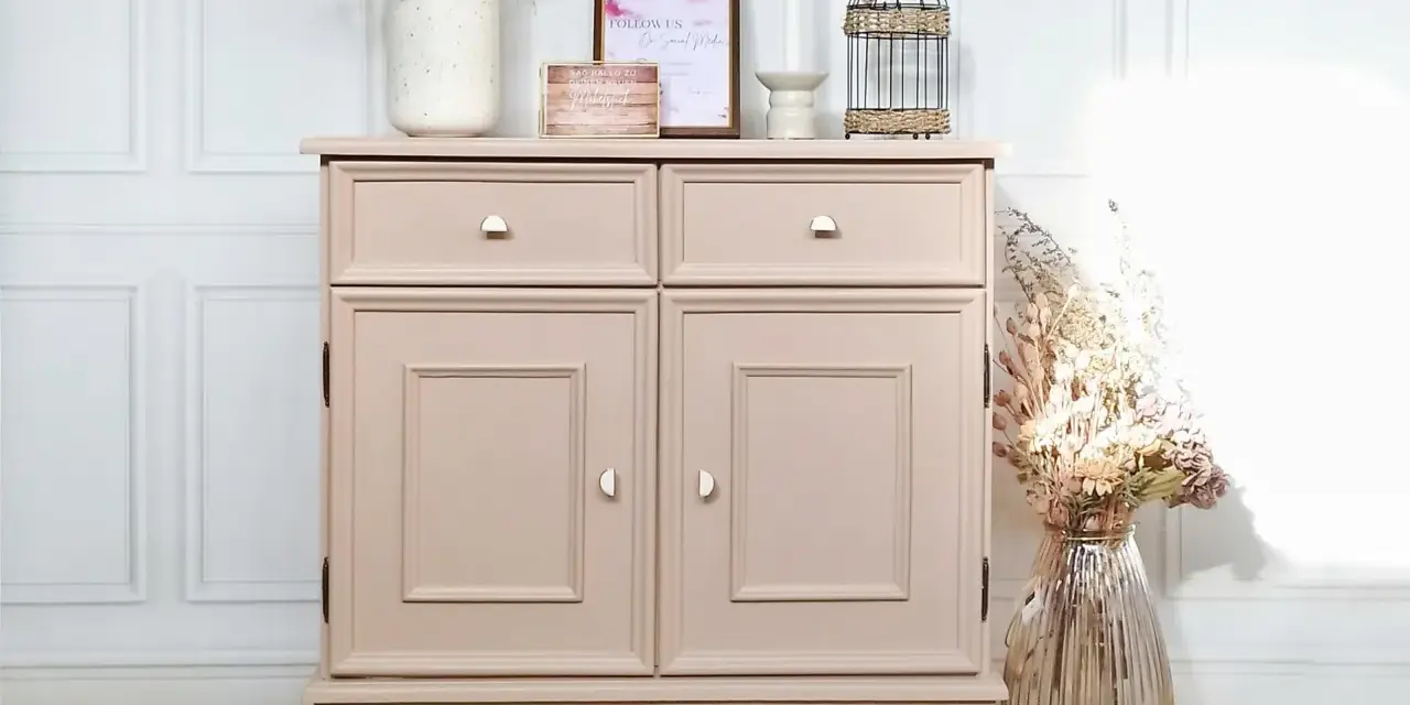 Meuble vintage repeint en rose poudré, prêt à peindre sur ancienne peinture bois. Décoré de fleurs séchées et d'une cage décorative.