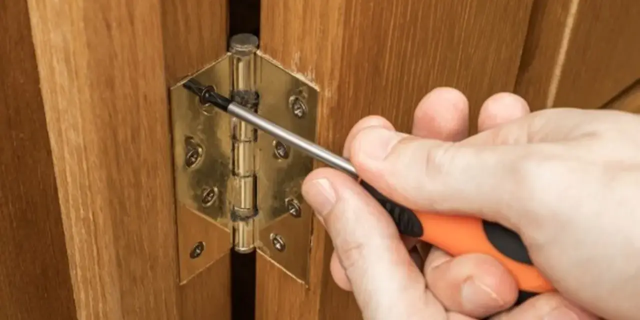 Réglage d'une charnière de porte de placard en bois avec un tournevis. Quelle charnière pour porte placard choisir ?