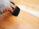 Application d'un vernis protecteur pour le traitement plan de travail bois. La brosse dépose une couche uniforme sur le bois clair.
