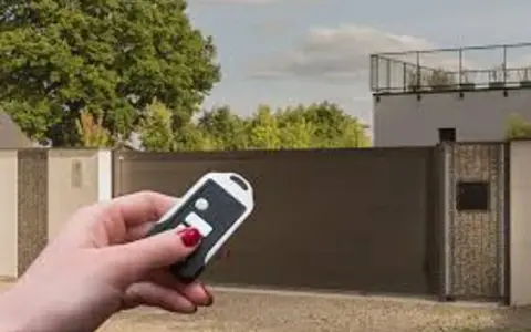 Main tenant utilise une télécommande pour le réglage du gond d'un portail aluminium.