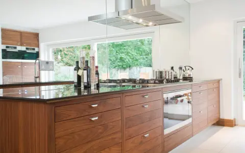 Cuisine moderne avec îlot central en bois, plan de travail en granit noir, et électroménagers intégrés. Une rénovation cuisine bois réussie.