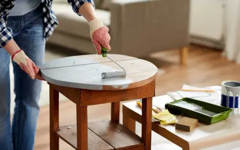 Application d'une sous-couche grise sur une table en bois. Le résultat avant/après du decapant bois est visible.