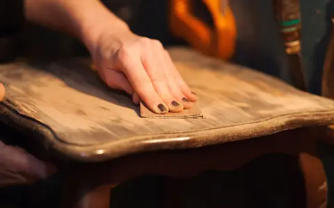 Main poncée pour enlever vernis bois. Le bicarbonate de soude peut aider à décaper.