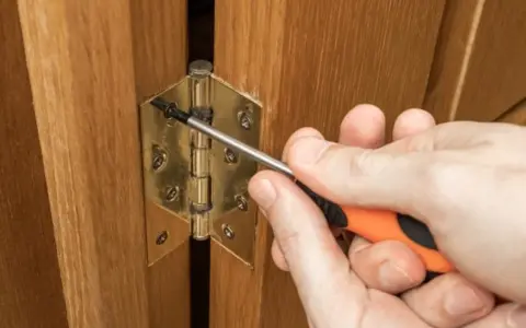 Réglage d'une charnière de porte de placard en bois avec un tournevis. Quelle charnière pour porte placard choisir ?