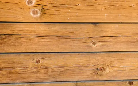 Planches de bois brun clair, traitées avec une lasure bois autoclave, révélant des nœuds et des veines naturelles.