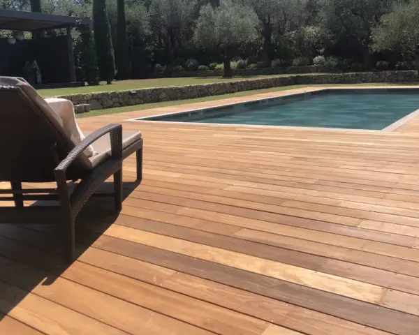 Terrasse en bois ipe vieilli, invitant à la détente au bord de la piscine sous le soleil.