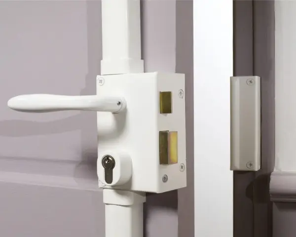 Poignée et serrure blanche avec barillet visible, prête à être verrouillée. Une clé de chaque côté assure la sécurité.