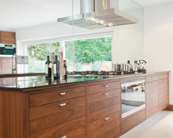 Cuisine moderne avec îlot central en bois, plan de travail en granit noir, et électroménagers intégrés. Une rénovation cuisine bois réussie.
