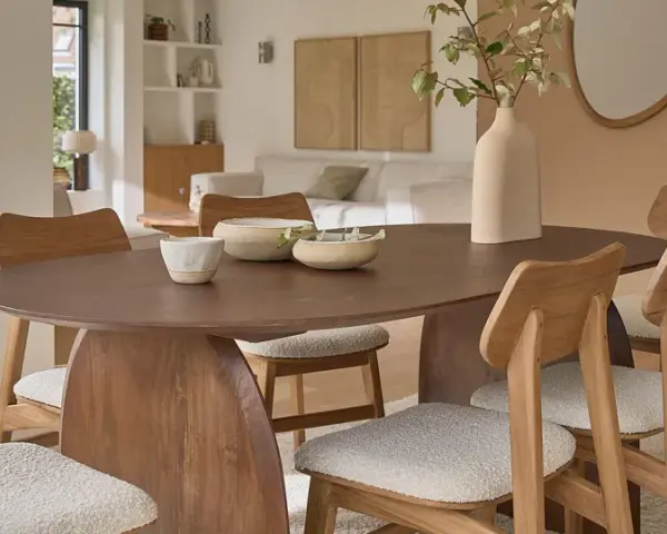Table et chaises en bois mindi dans une salle à manger lumineuse. Des bols décoratifs et une plante apportent une touche naturelle.