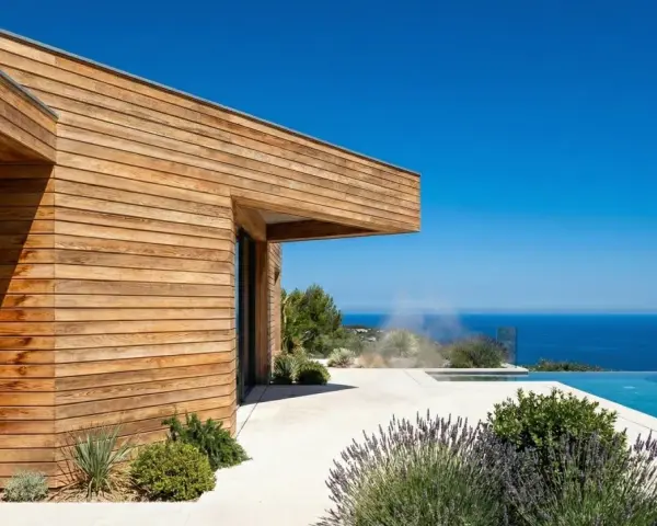 Maison moderne aux parements en bois de douglas ou pin, avec piscine à débordement et vue sur la mer.