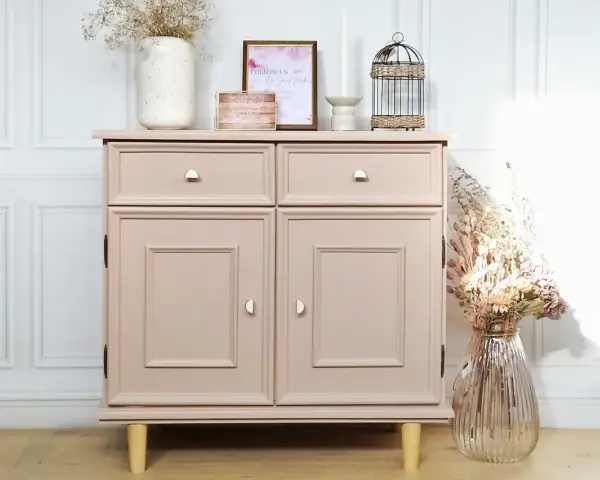 Meuble vintage repeint en rose poudré, prêt à peindre sur ancienne peinture bois. Décoré de fleurs séchées et d'une cage décorative.