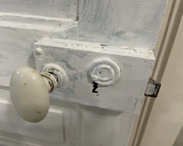 Poignée de porte ancienne et serrure en cours de préparation pour décaper une porte en bois peinte.