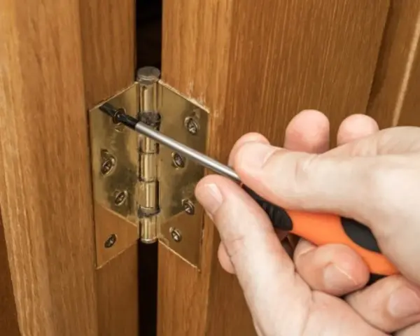 Réglage d'une charnière de porte de placard en bois avec un tournevis. Quelle charnière pour porte placard choisir ?