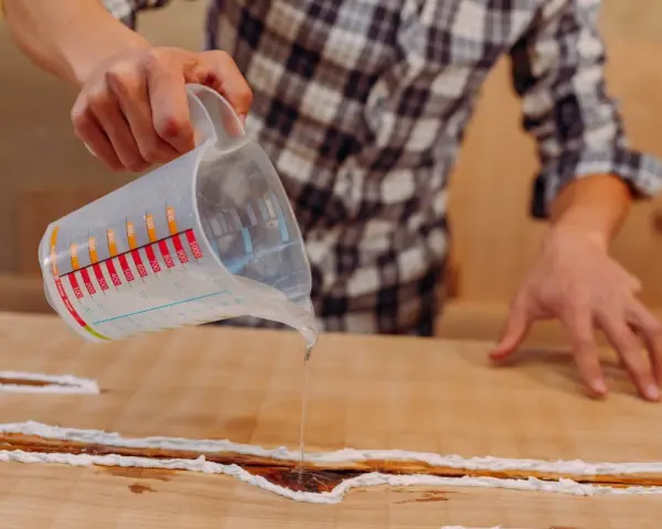 Application d'une résine transparente sur un meuble bois gonflé par l'eau, pour le restaurer et le protéger.