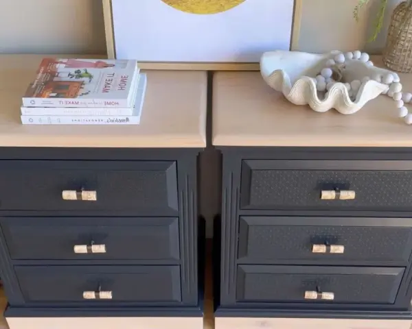 Deux commodes relookées noir et bois, avec des poignées en rotin, des livres et une coquille décorative.
