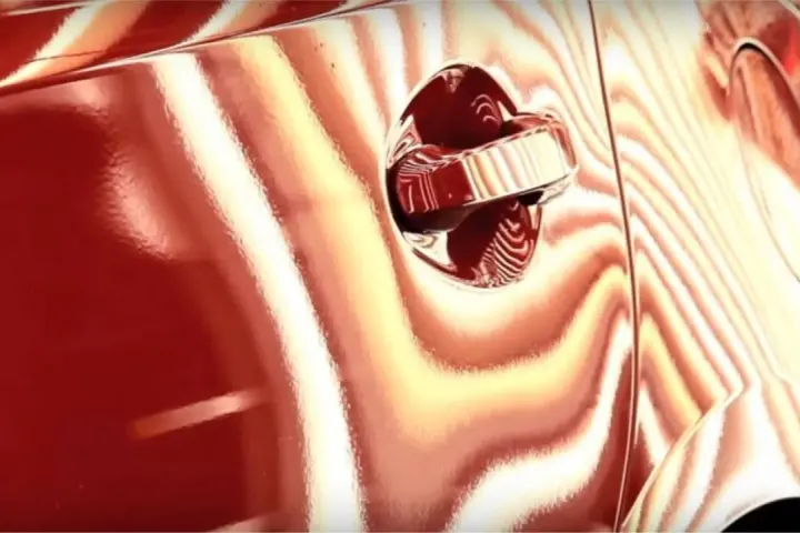 La peinture rouge d'une voiture présente des reflets ondulés, comme pour supprimer l'effet peau d'orange.