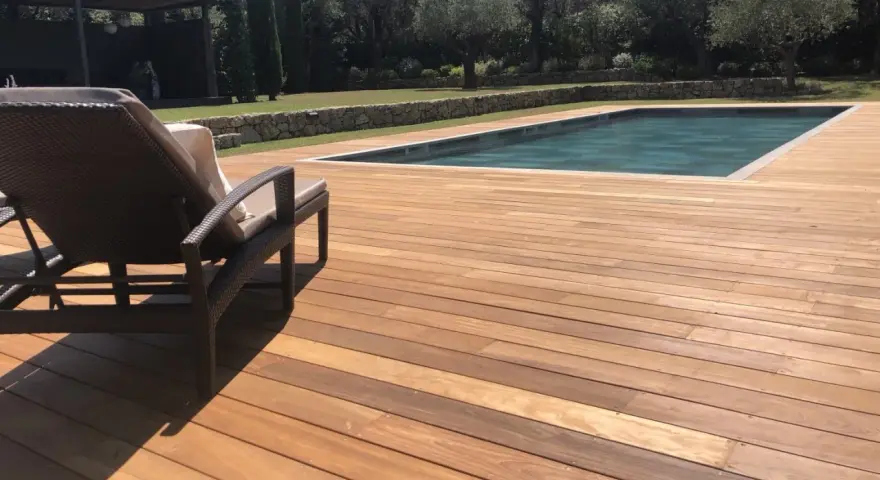 Terrasse en bois ipe vieilli, invitant à la détente au bord de la piscine sous le soleil.