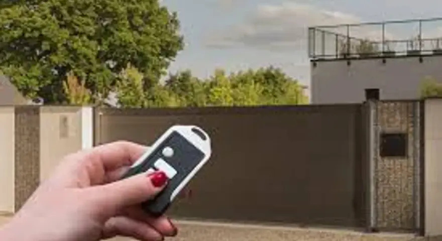 Main tenant utilise une télécommande pour le réglage du gond d'un portail aluminium.