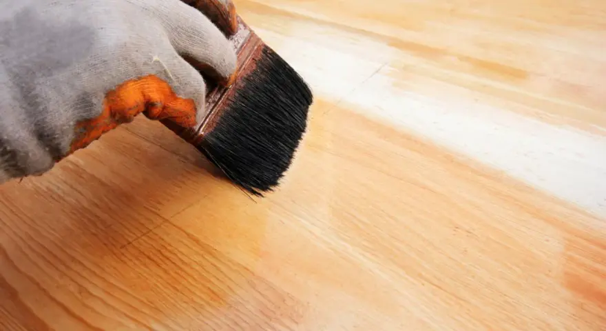 Application d'un vernis protecteur pour le traitement plan de travail bois. La brosse dépose une couche uniforme sur le bois clair.