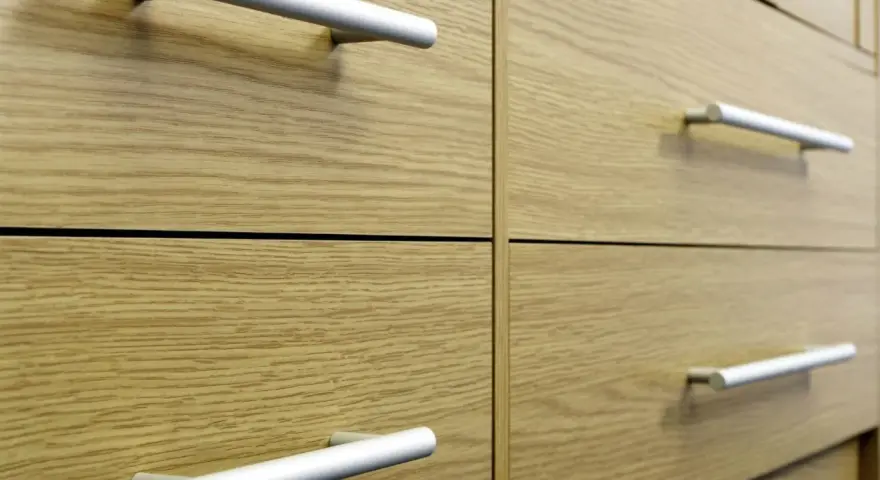 Poignées de tiroirs en aluminium sur des meubles en bois clair. Un guide visuel pour comment fixer un bouton de meuble.