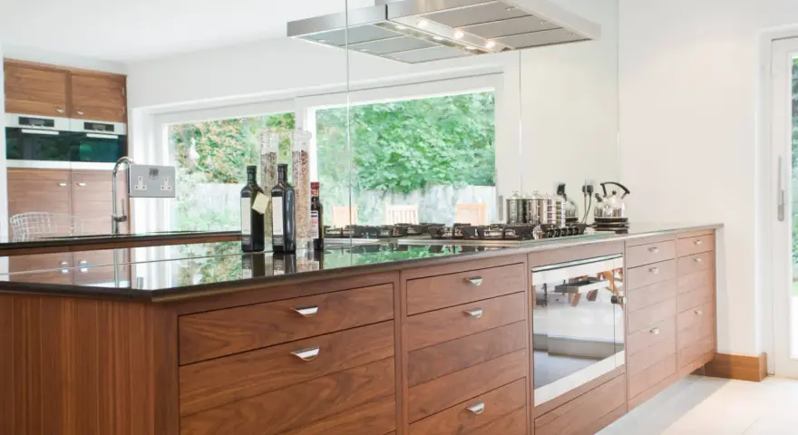 Cuisine moderne avec îlot central en bois, plan de travail en granit noir, et électroménagers intégrés. Une rénovation cuisine bois réussie.